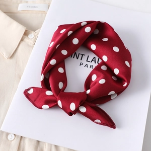 Luxurious red satin silk scarf with white polka dot pattern on beige shirt background