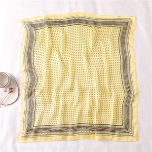 Vue détaillée d'un foulard carré en soie jaune avec des motifs géométriques noirs rétro