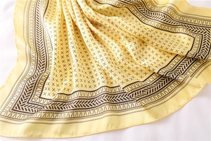 Gros plan détaillé d'un foulard en soie jaune clair avec motifs géométriques noirs et reflets