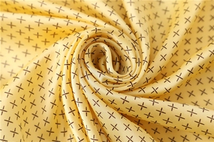 Détail macro d'un foulard en soie jaune clair avec motifs en croix et texture satinée