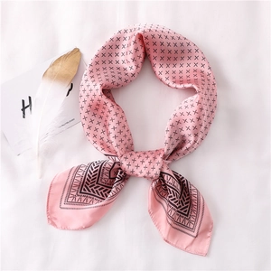 Détail d'un foulard en soie rose avec motifs en X et bordure ethnique sur tissu blanc