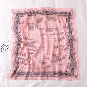 Détail du foulard carré en soie rose avec motifs géométriques noirs et bordure élégante
