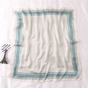 Détail d'un foulard carré en soie avec motifs géométriques verts et bordure rétro chic