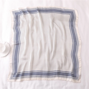 Gros plan d'un foulard carré en soie 70x70cm avec motifs géométriques bleu marine sur beige
