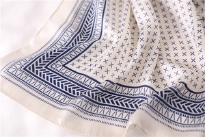 Détail de motif géométrique bleu marine sur foulard en soie crème et satiné