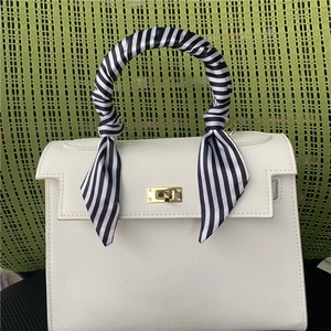Detail of white lychee leather bag handle wrapped with black and white striped silk scarf