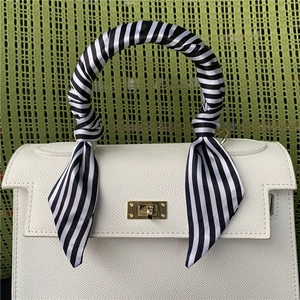 White lychee pattern handbag with a striped silk scarf wrapped around the top handle