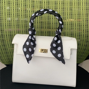 Detail of white lychee leather handbag handle wrapped with black and white polka dot scarf