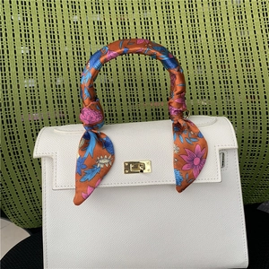 Detail of printed silk scarf wrapped on white pebbled leather bag handle with gold lock