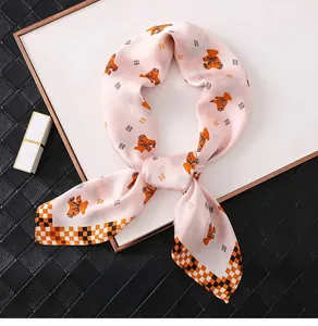 Detail of pink silk scarf showing cartoon bear patterns and checkerboard borders