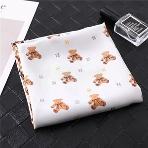 Detail view of white silk scarf featuring teddy bear print and geometric pattern