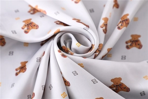 Macro shot of silk texture fabric featuring cute teddy bear and classic plaid patterns