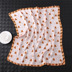 Detail of light pink silk square scarf with bear print and checkered border on black background