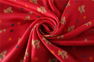 Detail of red satin scarf showing teddy bear print and 4G logo with smooth texture