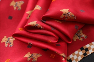 Detail of red satin scarf showing teddy bear prints and luxury check border texture