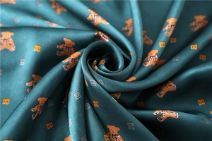 Macro detail of dark green silk fabric with teddy bear print and glossy satin texture
