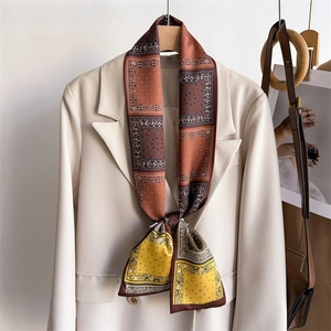 Foulard en soie rétro paisley noué comme une cravate étroite sur un blazer beige