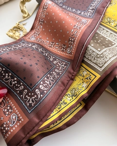 Gros plan d'un foulard en soie vintage avec motif paisley aux tons marron et orange