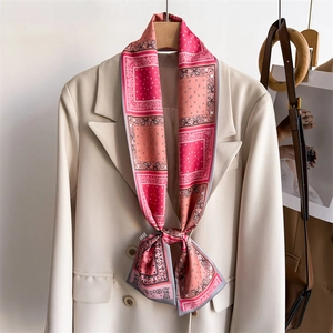 Foulard en soie rose à motif paisley porté en cravate sur un blazer beige
