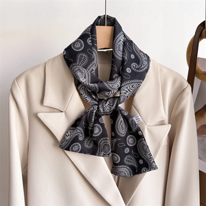 Élégant foulard en soie noir à motif paisley noué sur un revers de veste beige
