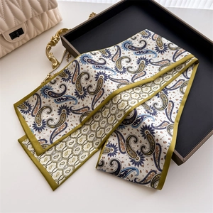 Détail d'un foulard en soie à motif paisley avec bordure verte sur un plateau rétro