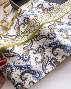 Détail d'un foulard en soie à motif paisley bleu et jaune sur fond blanc