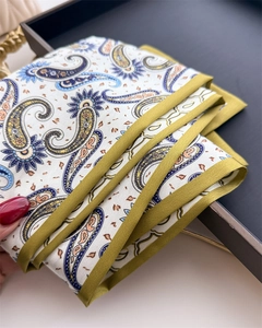 Détail d'un foulard en soie à motif cachemire avec bords roulés sur un plateau