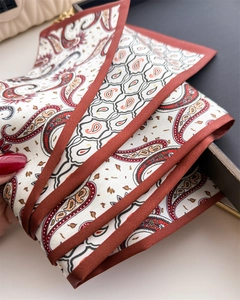 Détail d'un foulard en soie à motif paisley avec bords roulés rouges sur un sac