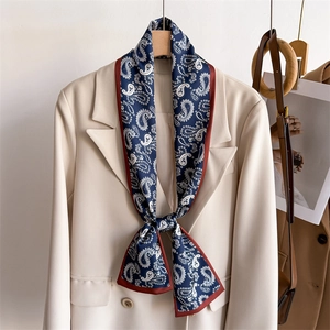 Navy blue paisley skinny silk scarf tied on a beige suit collar for fashion styling