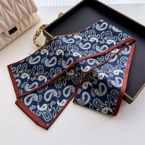 Détail d'un foulard étroit en soie à motif paisley bleu marine avec bordure bordeaux