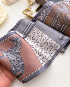 Close-up of silk scarf with equestrian horse and bridle print on light background