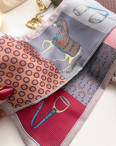 Macro detail of equestrian print silk scarf showing twill texture and horse motifs