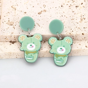 Détail de boucles d'oreilles ours vert menthe avec inscription Honey sur acrylique