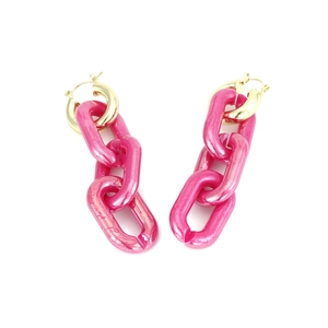 Close-up of long hot pink acrylic chain earrings with golden round hooks on white background