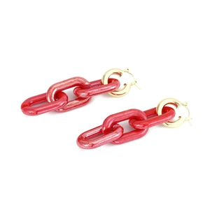 Detail of red resin chain link earrings with golden clasp on white background