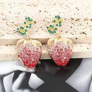 Detailed view of strawberry earrings with vibrant colorful rhinestones on a stone surface