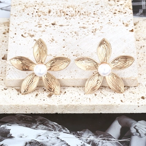 Bohemian gold flower earrings with pearls on natural stone background, floral stud jewelry