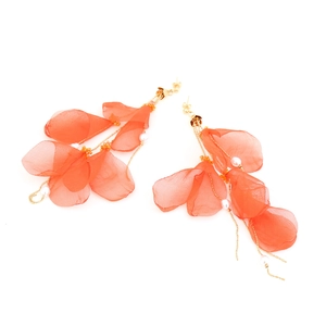 Close-up of bohemian orange chiffon petal earrings with pearls and long gold chains