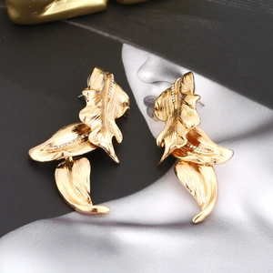 Vintage golden leaf earrings with brushed metal finish and rhinestone accents on magazine
