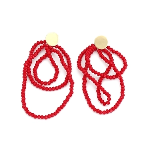 Detail of red faceted glass bead tassel earrings with golden round metallic studs