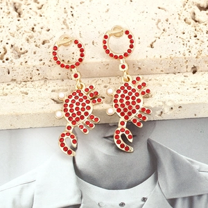 Boucles d'oreilles crabe dorées avec strass rouges et perles sur support en pierre