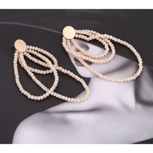 Detail of layered champagne beaded tassel earrings with gold metal base and faceted beads