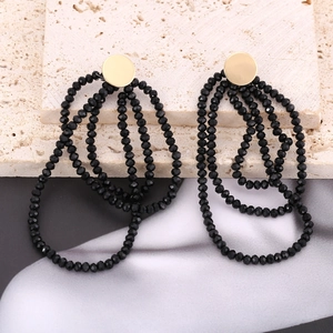 Close-up of bohemian layered black crystal bead tassel earrings on stone background