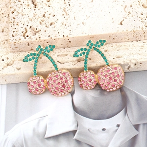 Sparkling cherry drop earrings with pink and green crystals on a stylish stone surface
