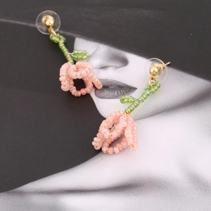 Macro shot of handmade beaded tulip earrings with pink petals and green leaves