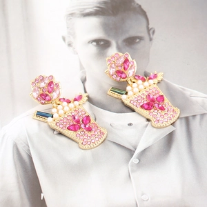 Close-up of floral alloy earrings with pink rhinestones and white pearls on a magazine page