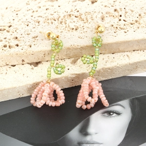 Close-up of handmade beaded floral earrings with pink-orange petals and green beads