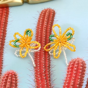 Bohemian colorful flower beaded earrings set on cactus prop against blue background