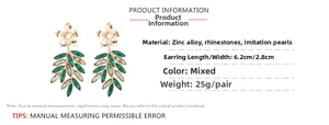 Detailed view of leaf earrings featuring green marquise crystals and gold flower studs