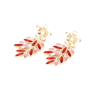Close-up of gold-tone floral leaf earrings with red and pink crystals and pearls